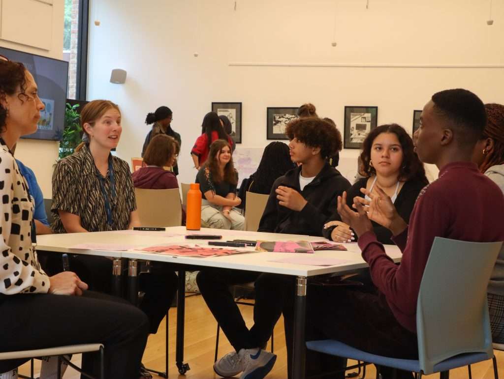A group of young people sitting around a table smiling and chatting together.